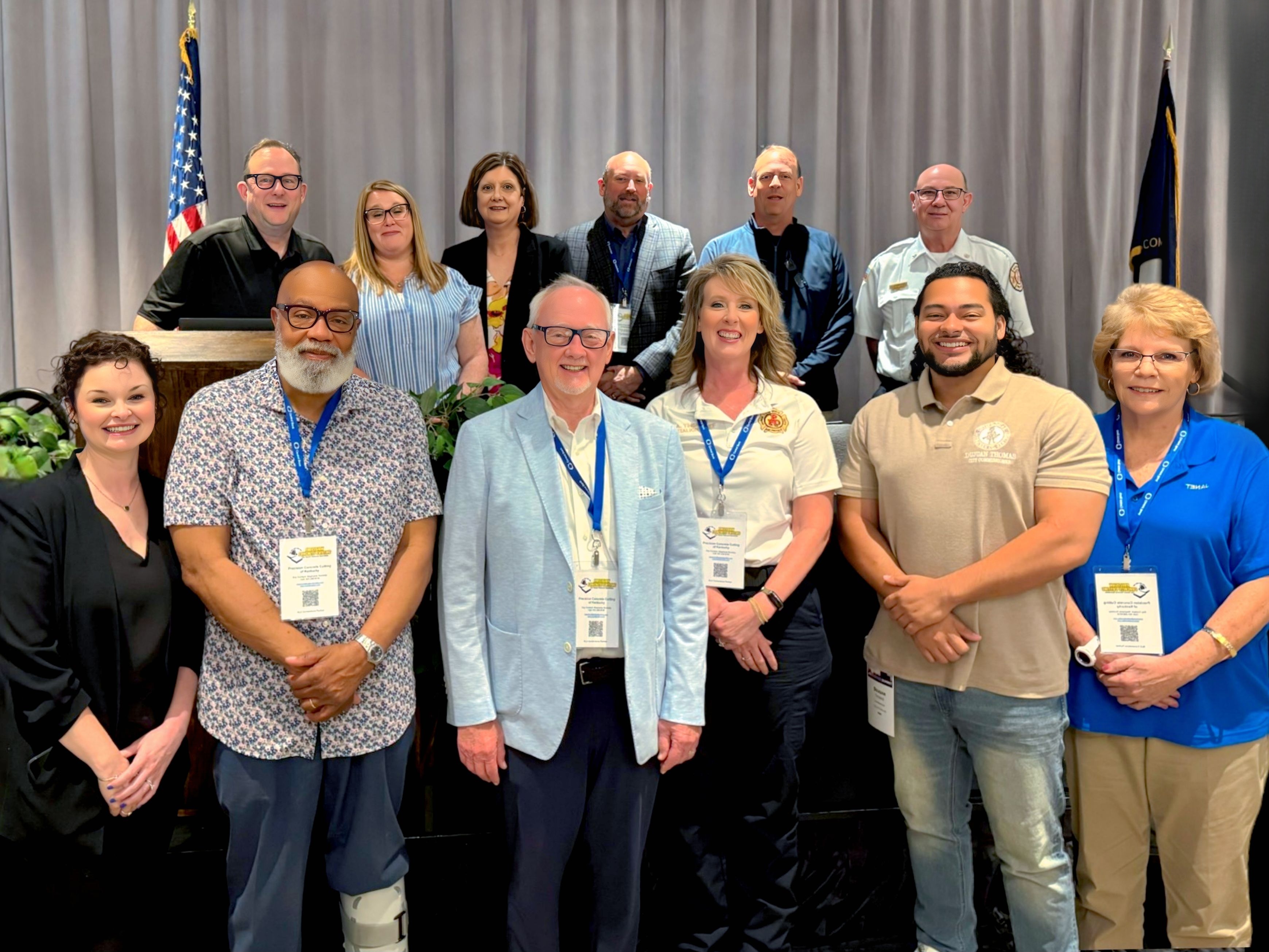 photo of city of paducah team and partner agencies standing in two rows in front of a grey curtain with U.S. and stage flags.